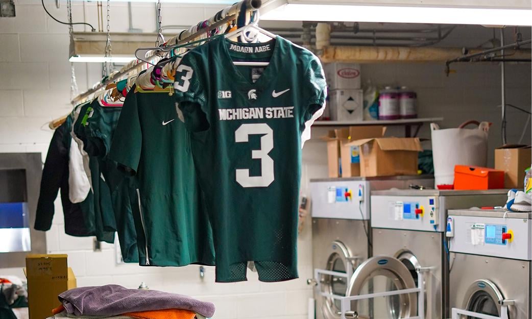 MSU football jerseys hang before washing. 