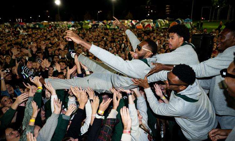 Members of Men's Basketball Team crowd surf. 