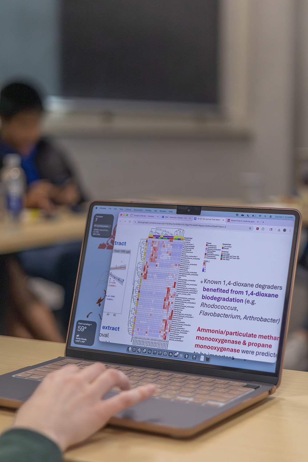 View of a laptop screen and keyboard with a single hand from the wrist up resting on the keyboard. There is a technical looking image displayed on the screen with illegible text to the right of it.