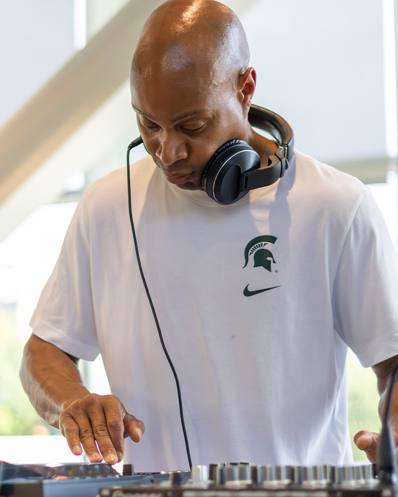 Person wearing headphones operates a DJ controller during a campus event.