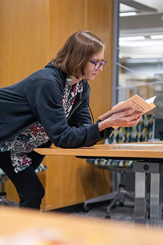 Participant reads a passage from a book in a meeting room.