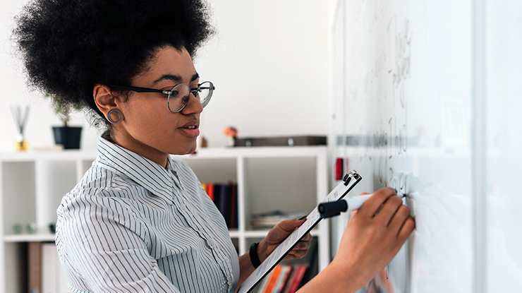Future educator writing on a classroom whiteboard as part of Michigan State University's French teaching degree program.