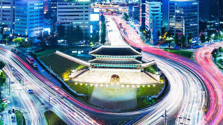 Nighttime aerial view of a historic Korean gate surrounded by city traffic, representing cultural exploration for students pursuing a major in Korean at MSU.