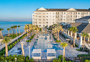 Long view of saltwater swimming pool with palm trees, cabanas and lounge chairs next to clubhouse at MAA Breakwater luxury apartments in Tampa, FL
