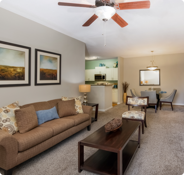Modern-style living room with rustic wood décor, brown couch and ceiling fan at MAA Barrett Creek luxury apartments in Marietta, GA