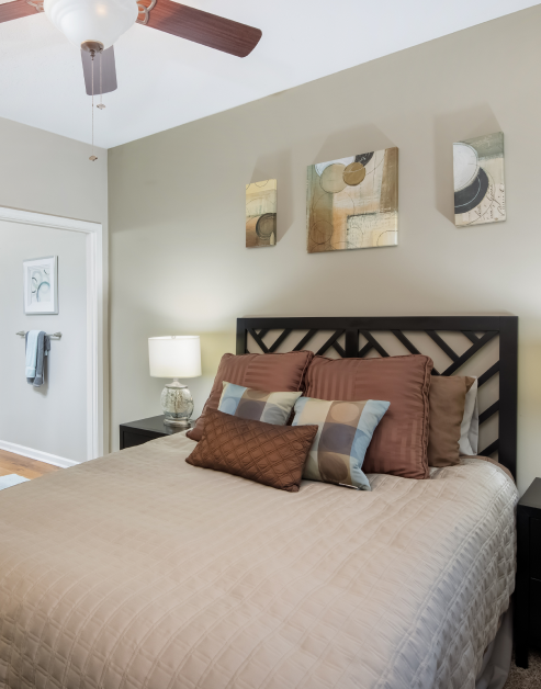 Cozy model bedroom with brown tone accent pillows and wall art at MAA Barrett Creek luxury apartments in Marietta, GA