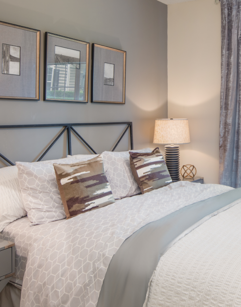 Model bedroom full-size bed with pillows and lighted night stand at MAA Briarcliff luxury apartments in Atlanta, GA