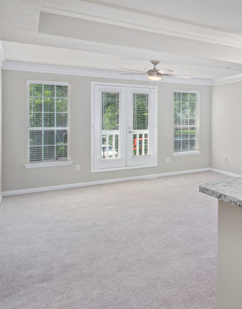 Wide open carpeted living room space with double doors exiting to balcony at MAA Briarcliff luxury apartments in Atlanta, GA