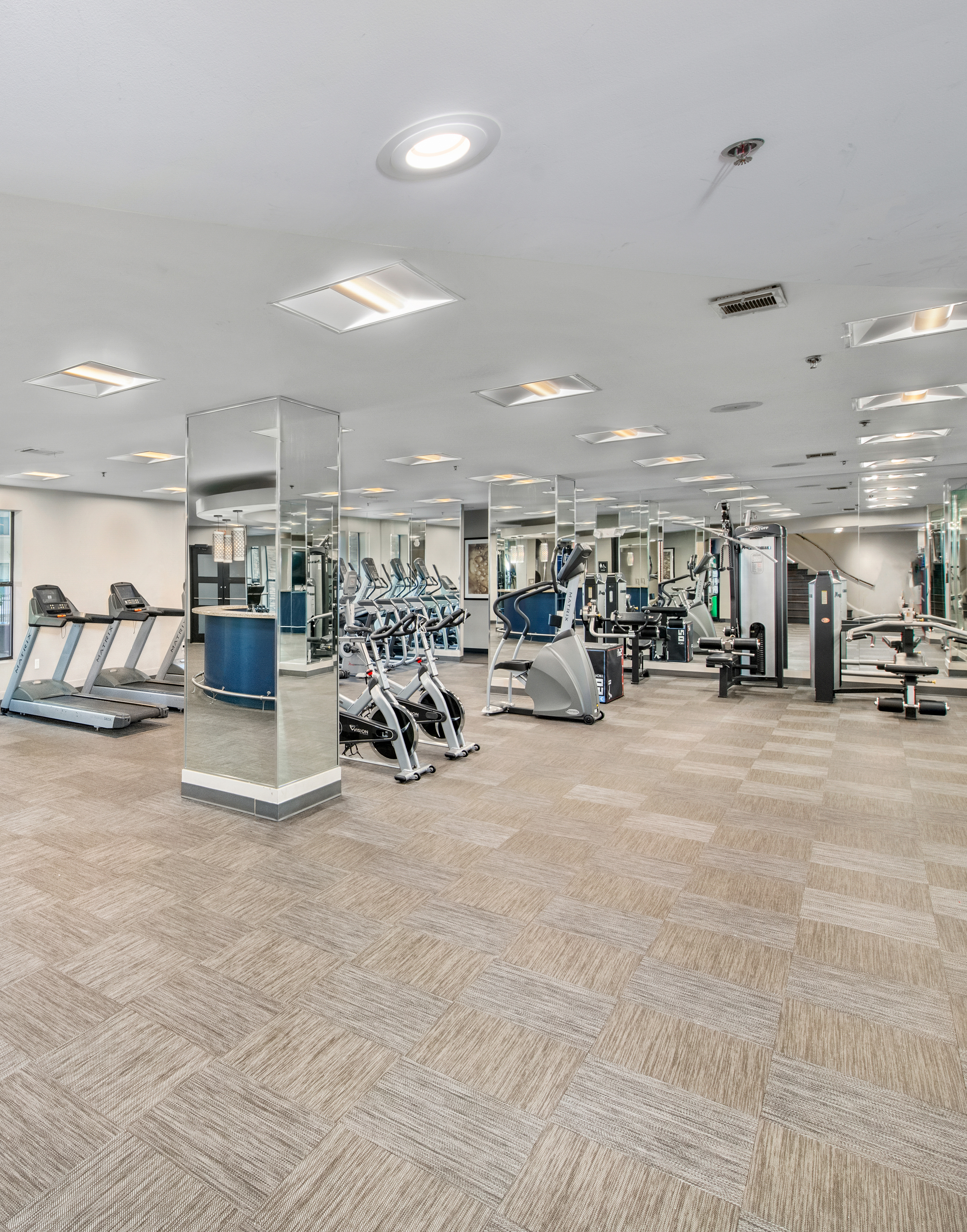 Community fitness center with mirrored columns and exercise machines on carpeted floors at MAA Brookwood luxury apartments in Atlanta, GA