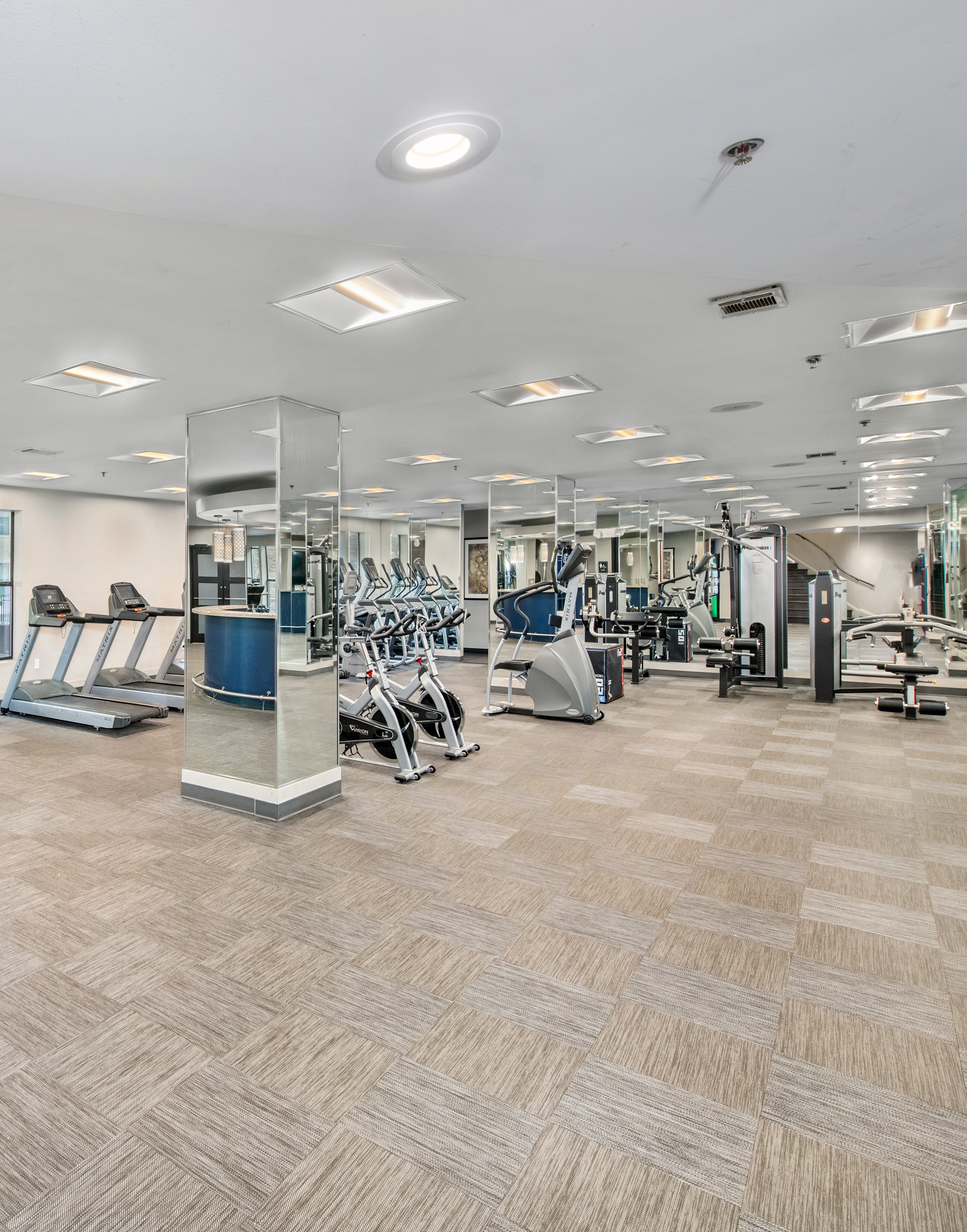 Community fitness center with mirrored columns and exercise machines on carpeted floors at MAA Brookwood luxury apartments in Atlanta, GA