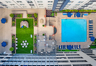 Aerial top down view of swimming pool with lounge chairs next to grassy patio area at MAA Buckhead luxury apartments complex in Atlanta, GA