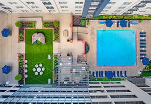 Aerial top down view of swimming pool with lounge chairs next to grassy patio area at MAA Buckhead luxury apartments complex in Atlanta, GA