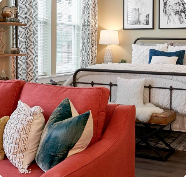 Model studio with full-size bed and a red couch at MAA Centennial Park luxury apartments in Atlanta, GA
