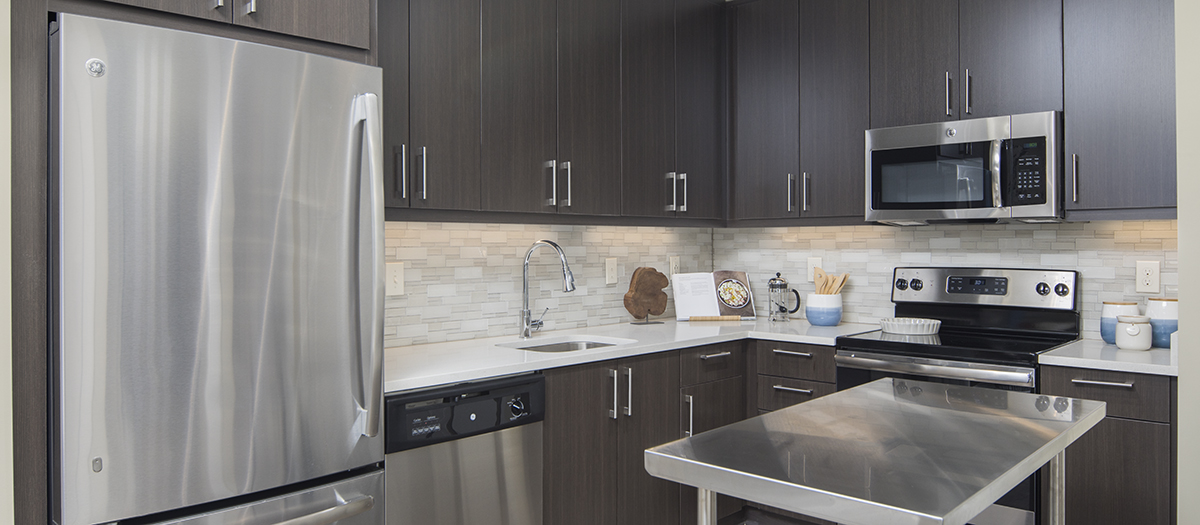 Kitchen with brown cabinets and stainless steel appliances at MAA Centennial Park luxury apartments in Atlanta, GA