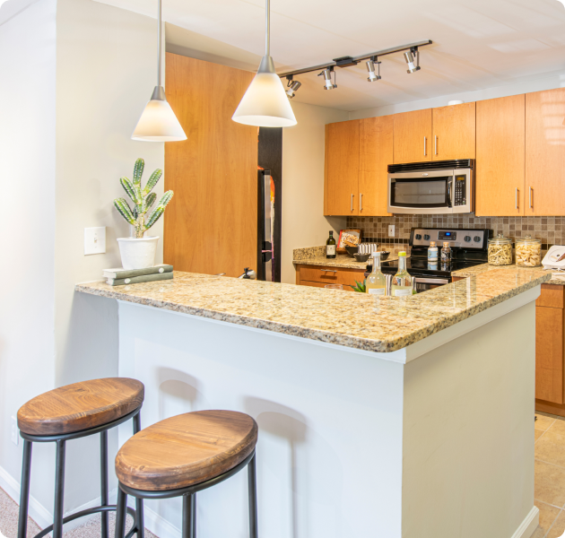 Modern kitchen granite bar top counter with wooden bar stools and ceiling lighting at MAA Chastain luxury apartments in Atlanta, GA