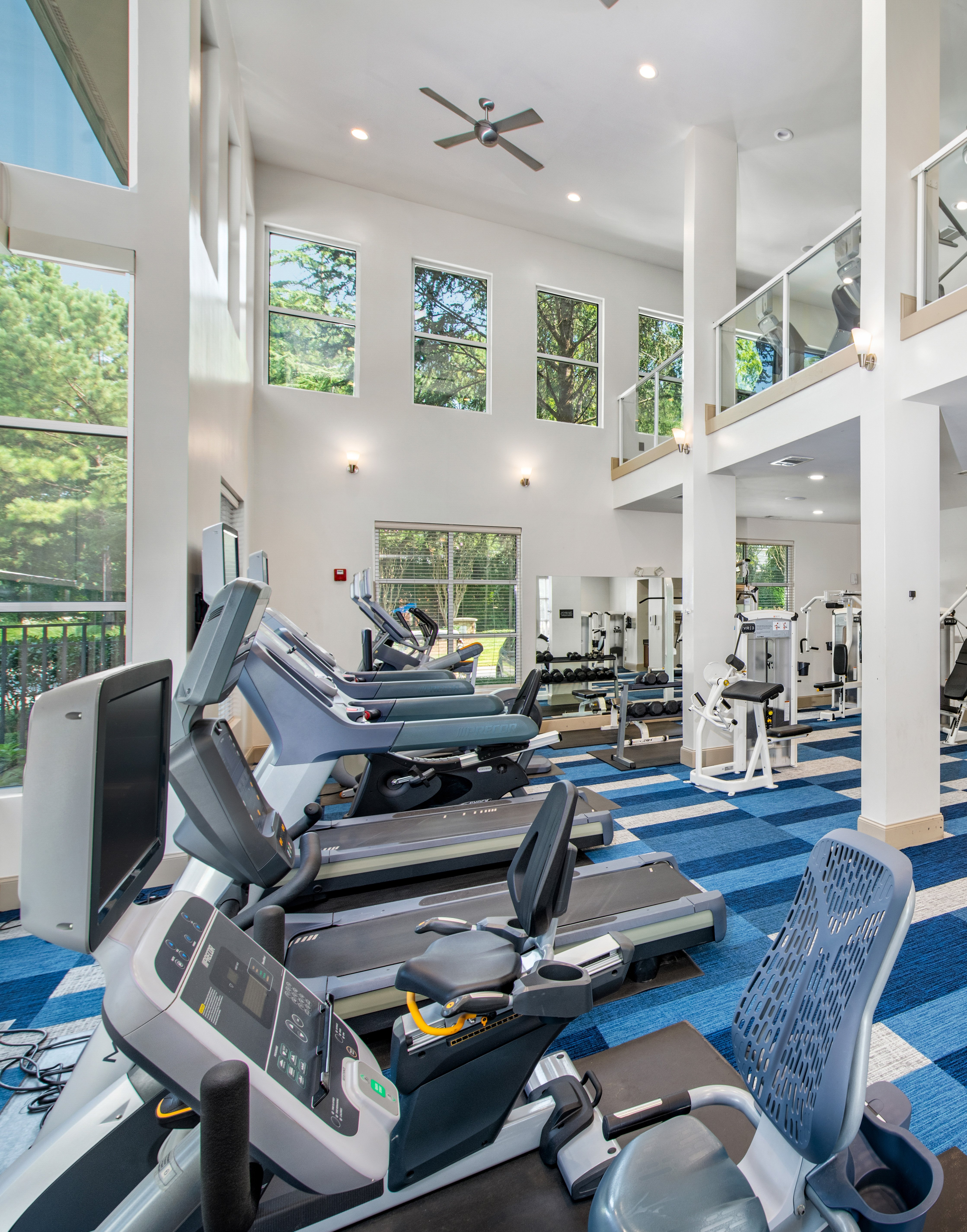 State-of-the-art two story fitness center complete with treadmills and weight machines next to large picture windows at MAA Chastain luxury apartments in Atlanta, GA