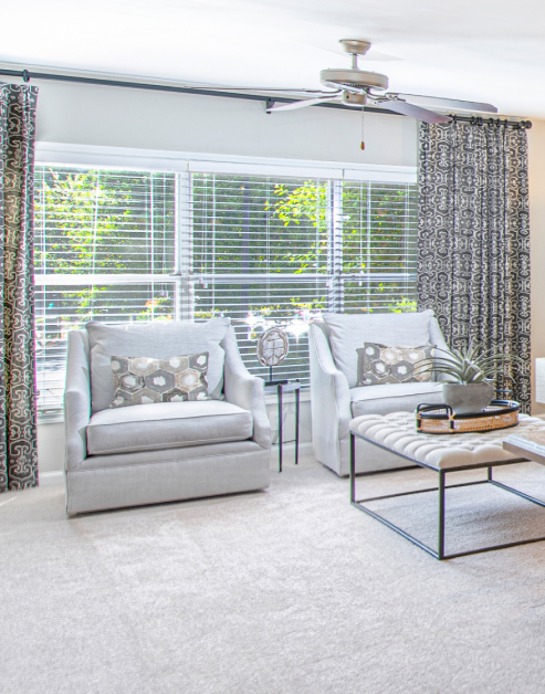 Spacious model living room with large picture windows, sofa chairs and ceiling fan in natural light at MAA Chastain luxury apartments in Atlanta, GA