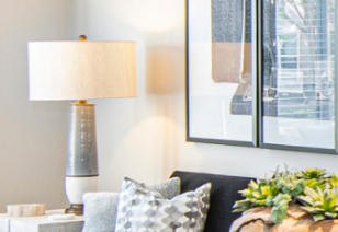 Model living room lit table lamp next to dark couch with accent pillows at MAA Chastain luxury apartments in Atlanta, GA