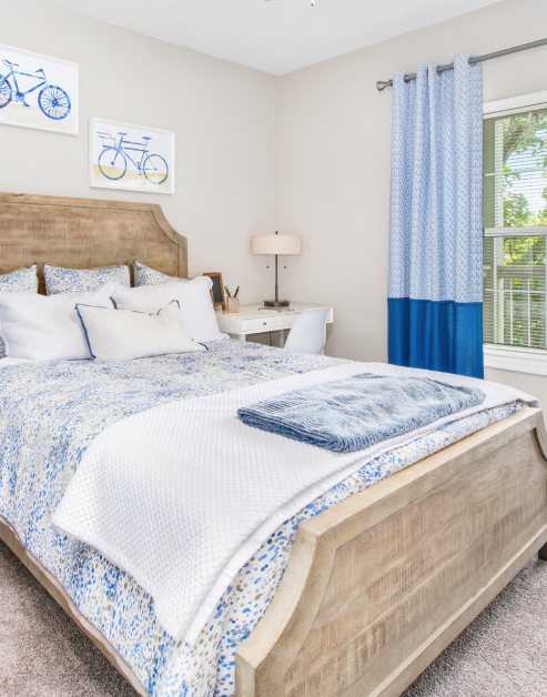 Model bedroom with blue/white bedding and writing desk at MAA Dunwoody luxury apartments in Atlanta, GA