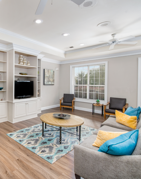 Community lounge with hard wood floors, built-in entertainment wall and ceiling fans at MAA Dunwoody luxury apartments in Atlanta, GA
