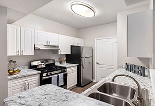 Modern kitchen with round ceiling dome light with white cabinets and stainless steel appliances at MAA Gardens luxury apartments in Atlanta, GA