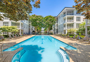 Long view of swimming pool with lounge chairs surrounded by trees at MAA Gardens luxury apartments in Atlanta, GA