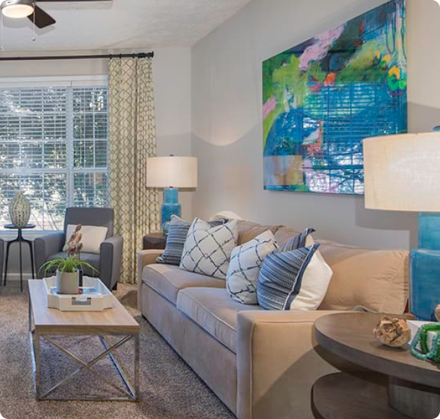 Spacious model living room with large picture windows, sofa chairs, couch and ceiling fan at MAA Glen luxury apartments in Atlanta, GA