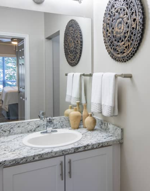 Modern-style bathroom with grey marble countertop, single vanity sink with large mirror and wall art at MAA Glen luxury apartments in Atlanta, GA
