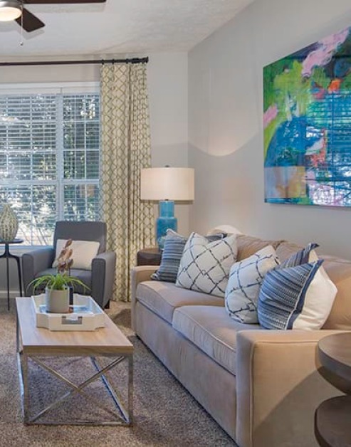 Model living room with large picture windows, sofa chairs, couch and ceiling fan at MAA Glen luxury apartments in Atlanta, GA
