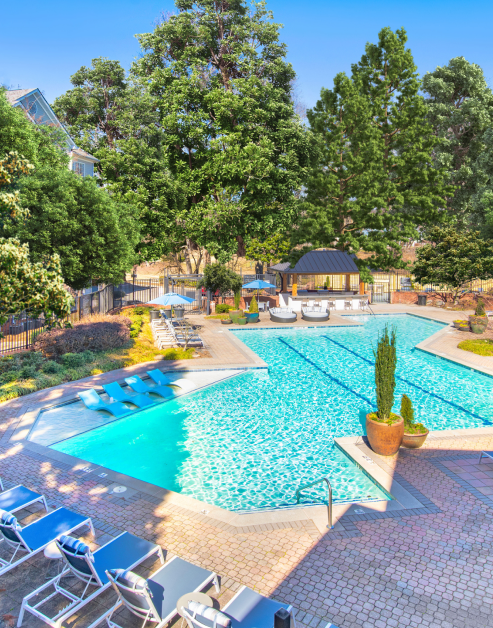 Resort-style swimming pool with sundeck and lounge chairs surrounded by lush greenery at MAA Glen luxury apartments in Atlanta, GA