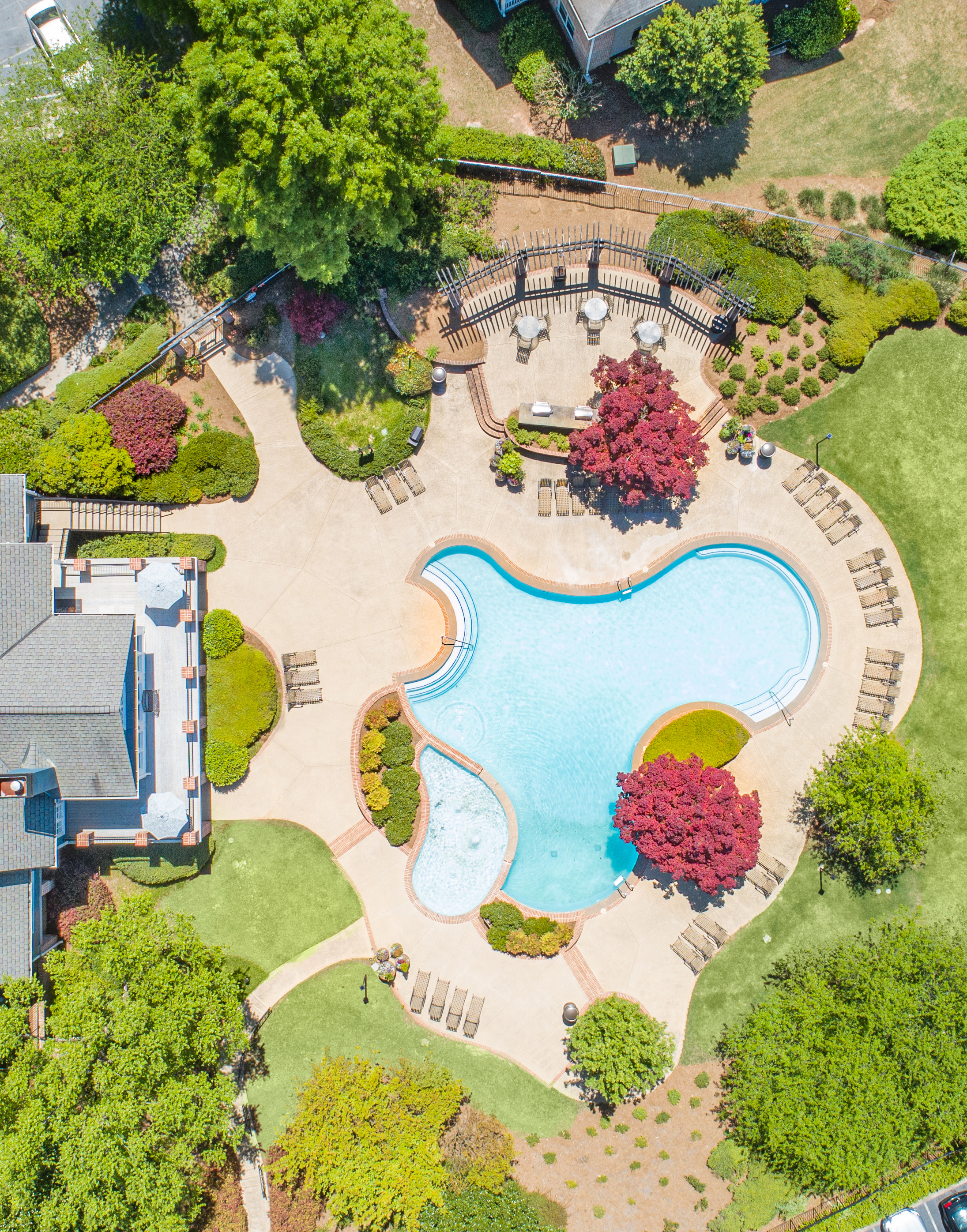 Aerial top view of swimming pool and hot tub surrounded by lounge chairs and greenery next to the clubhouse at MAA Lake Lanier luxury apartments in Gainesville, GA