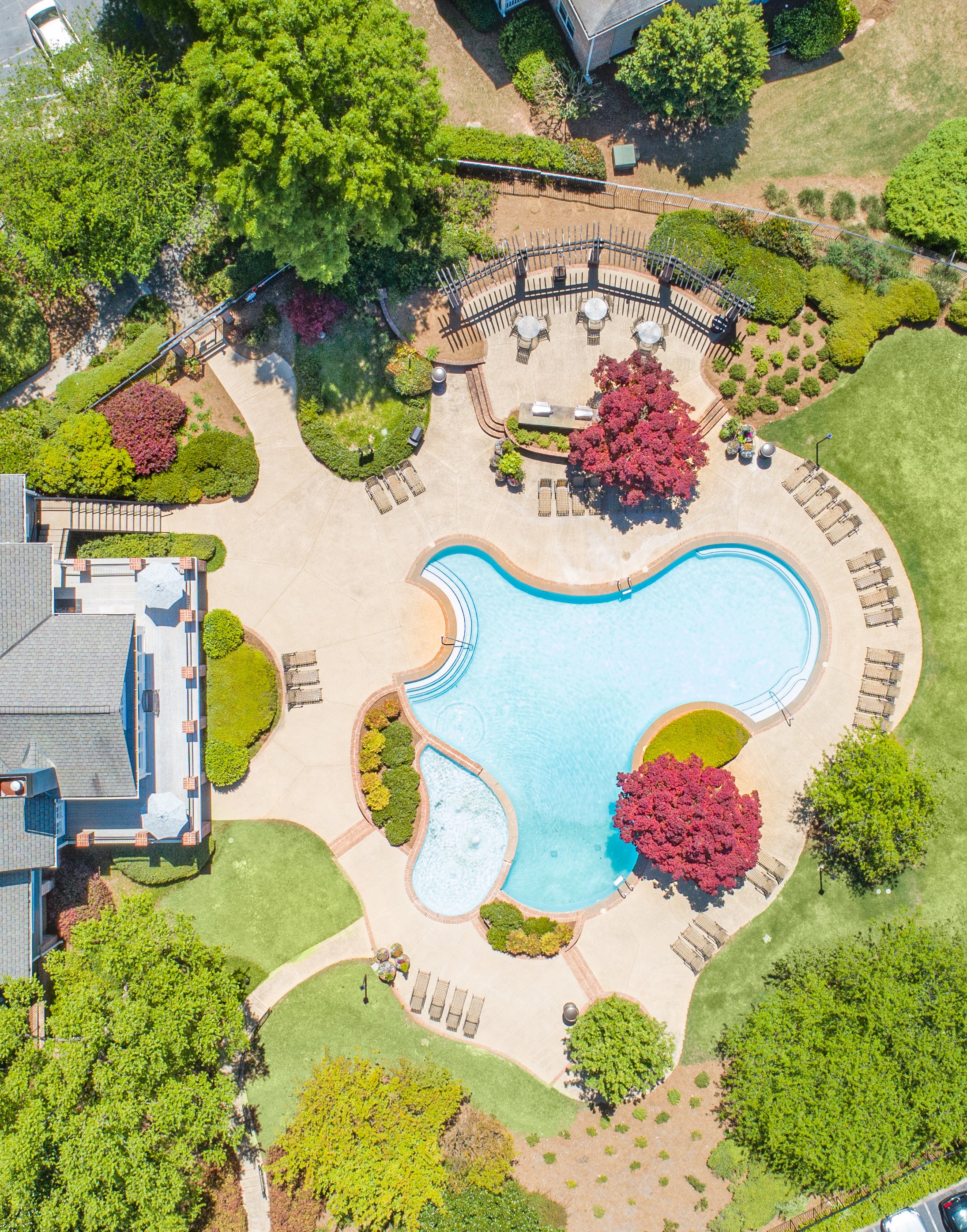 Aerial top view of swimming pool and hot tub surrounded by lounge chairs and greenery next to the clubhouse at MAA Lake Lanier luxury apartments in Gainesville, GA