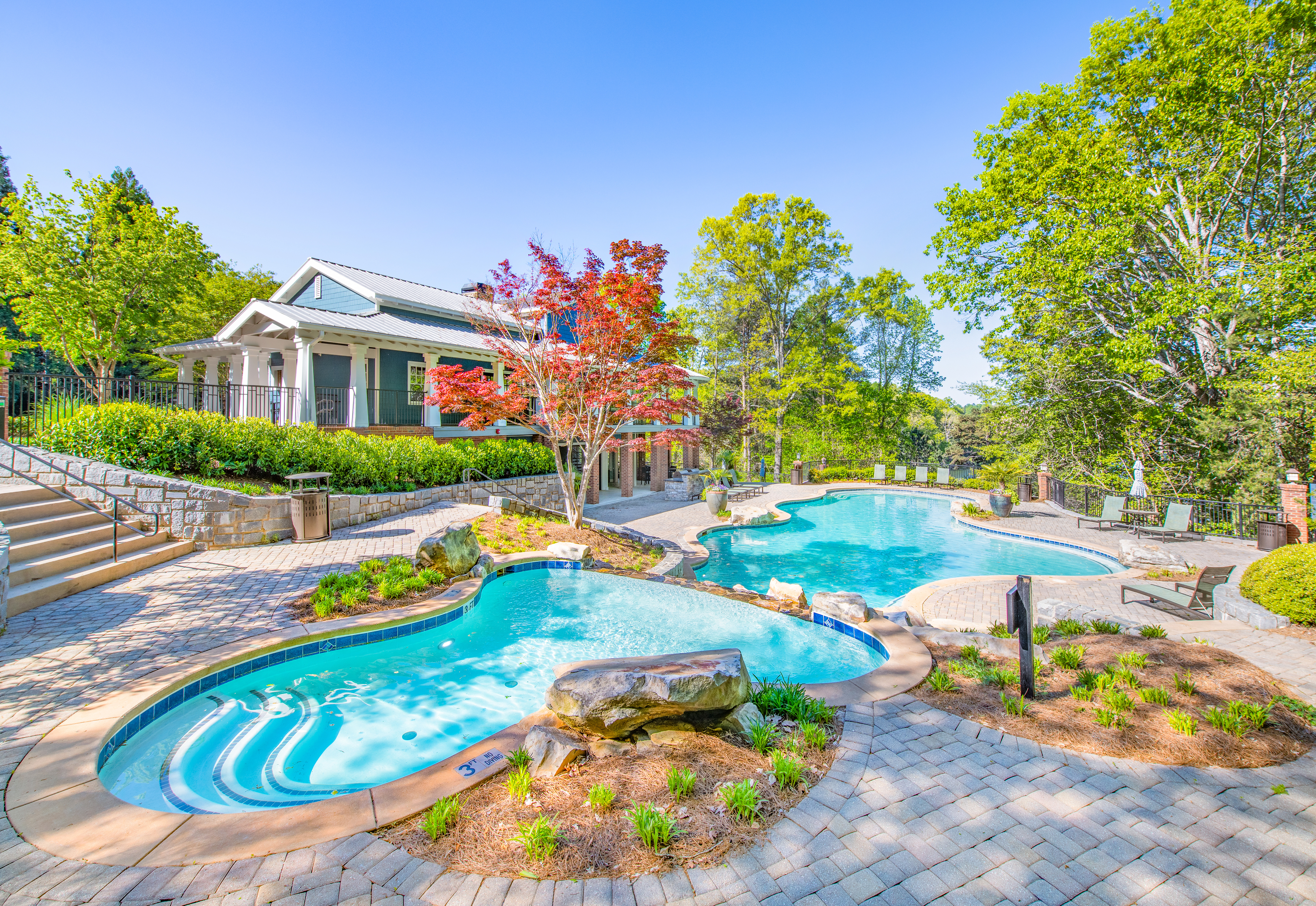 Long view of a double wading pool in the shade surrounded by planters and trees at MAA Lake Lanier luxury apartments in Gainesville, GA