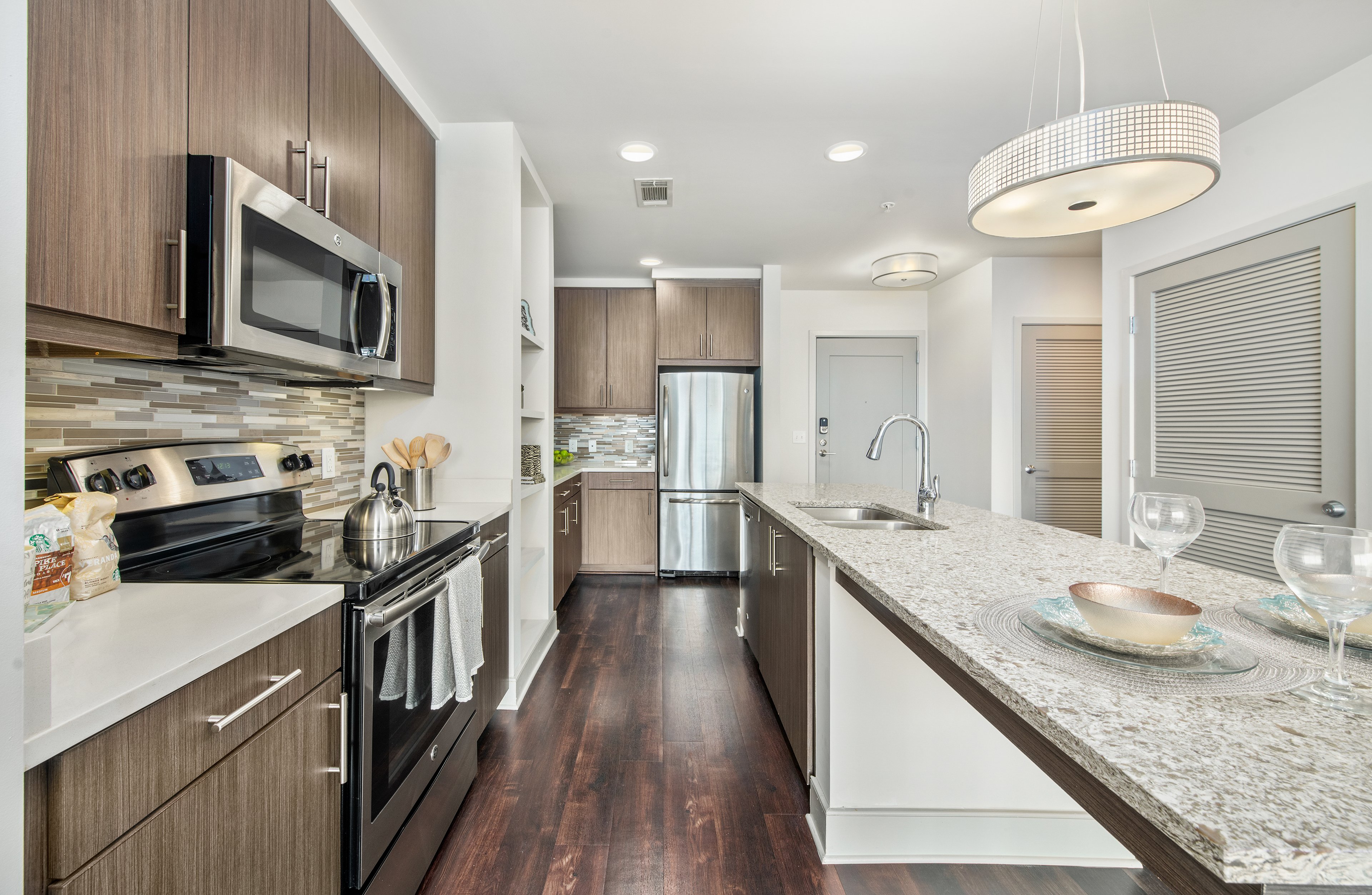 Side view of modern-style kitchen with stainless steel appliances, kitchen island and granite countertops at MAA Lenox luxury apartments in Atlanta, GA