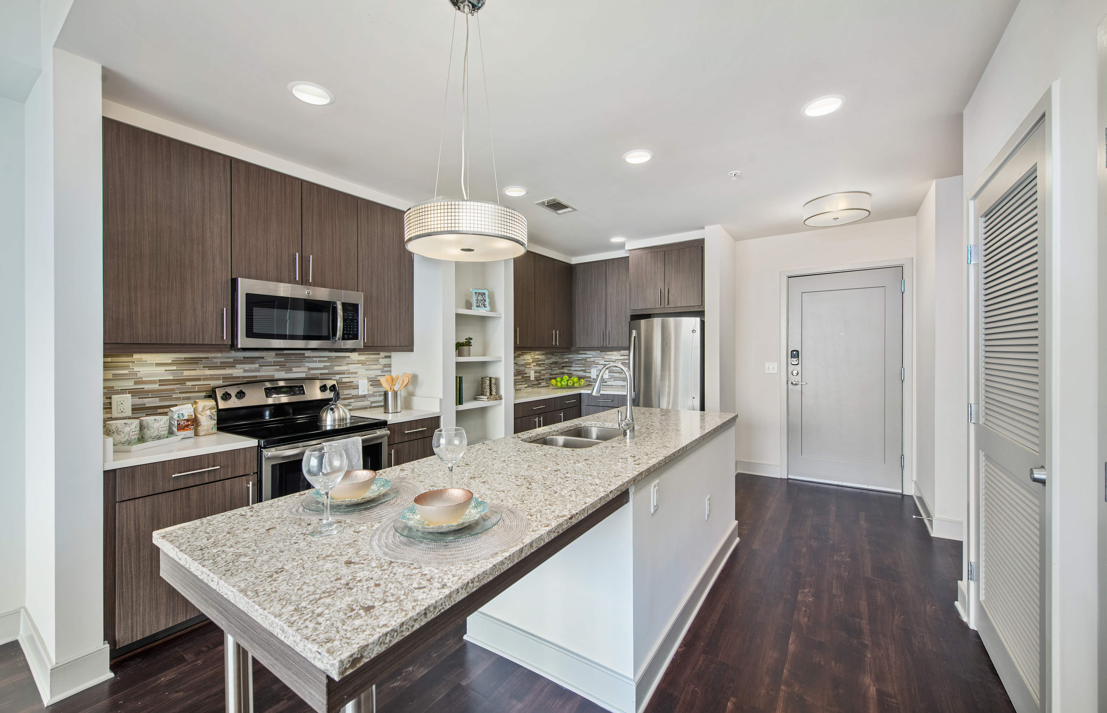 Front view of modern-style kitchen with stainless steel appliances, kitchen island with sink and granite countertops at MAA Lenox luxury apartments in Atlanta, GA