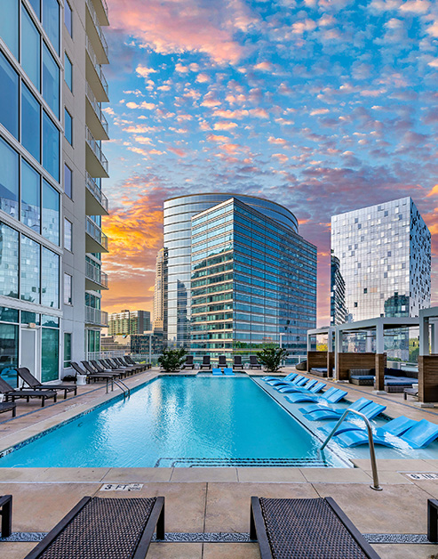 Outward view of rooftop wading pool with sun shelf surrounded by cabana-style lounging area at MAA Lenox luxury apartment homes in Atlanta, GA