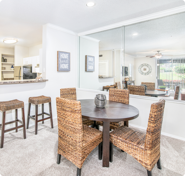 Rustic-style dining table with wicker chairs next to kitchen bar top at MAA McDaniel Farm luxury apartments in Duluth, GA