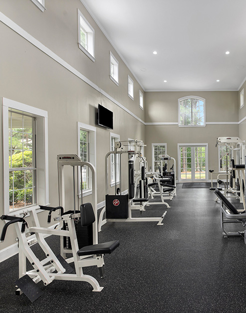 Community fitness center with various weight machines with multiple windows at MAA McDaniel Farm luxury apartments in Duluth, GA