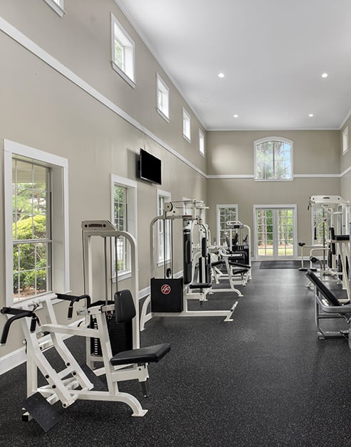 Community fitness center with various weight machines with multiple windows at MAA McDaniel Farm luxury apartments in Duluth, GA