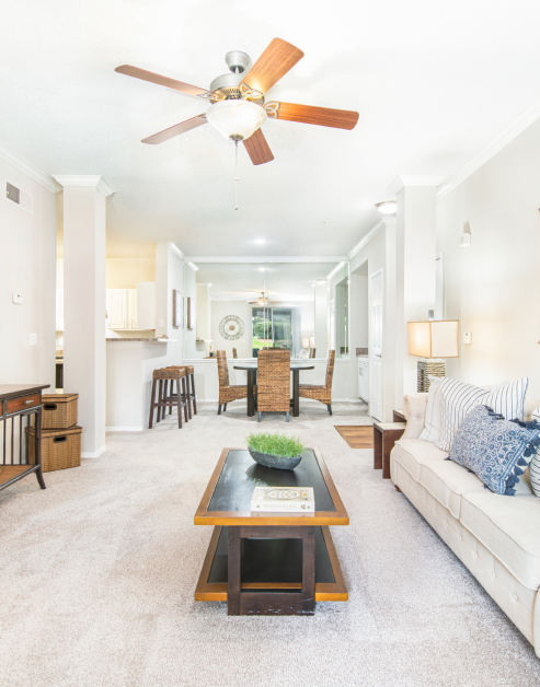 Rustic-style living room with white couch, dark coffee table and ceiling fan at MAA McDaniel Farm luxury apartments in Duluth, GA