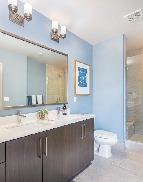 Modern bathroom with brown cabinets and double sink with vanity and blue walls at MAA Midtown luxury apartments in Atlanta, GA