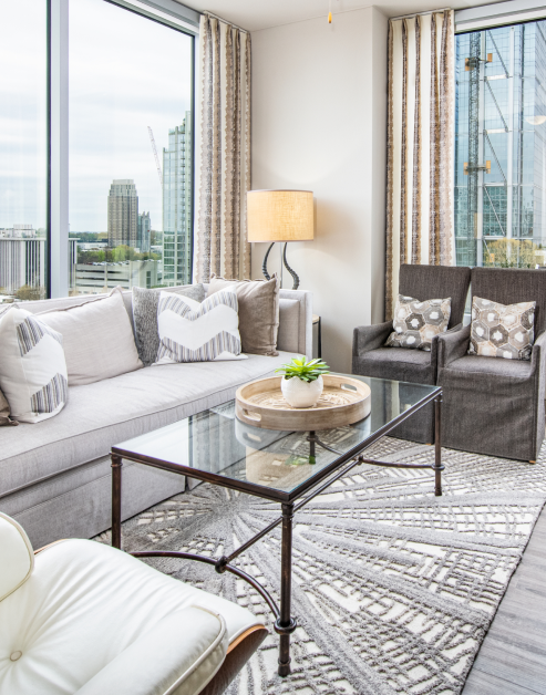 Stylish model living room with glass coffee table, city window views and white couch at MAA Midtown luxury apartments in Atlanta, GA