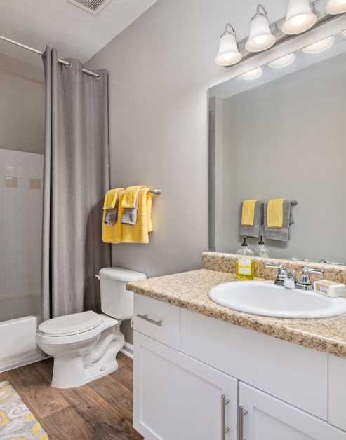 Modern bathroom with sink, large vanity mirror, brown marble countertop and white cabinets at MAA Milstead luxury apartments in Kennesaw, GA