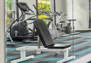 Fitness center weight machine bench next to mirrored walls at MAA Milstead luxury apartments in Kennesaw, GA