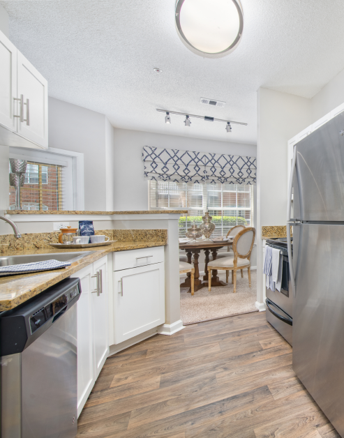 Modern open space kitchen with brown marble countertops, upgraded appliances and hard floors at MAA Milstead luxury apartments in Kennesaw, GA