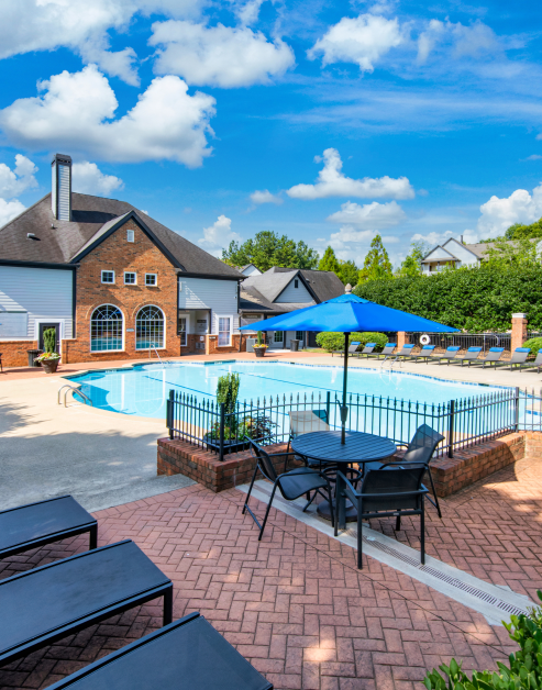 Swimming pool with lounge chairs, sun umbrella with table and chairs at MAA Milstead luxury apartments in Kennesaw, GA