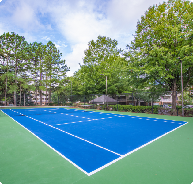 Community gated tennis court surrounded by lush trees at MAA Mount Vernon luxury apartments in Sandy Springs, GA