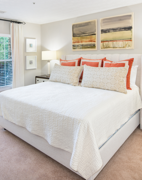 Model bedroom with white bedding, accent pillows and wall art at MAA Mount Vernon luxury apartments in Sandy Springs, GA