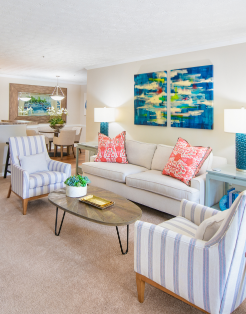 Modern-style living room with colorful wall art and white couch and stripped sofa chairs at MAA Mount Vernon luxury apartments in Sandy Springs, GA