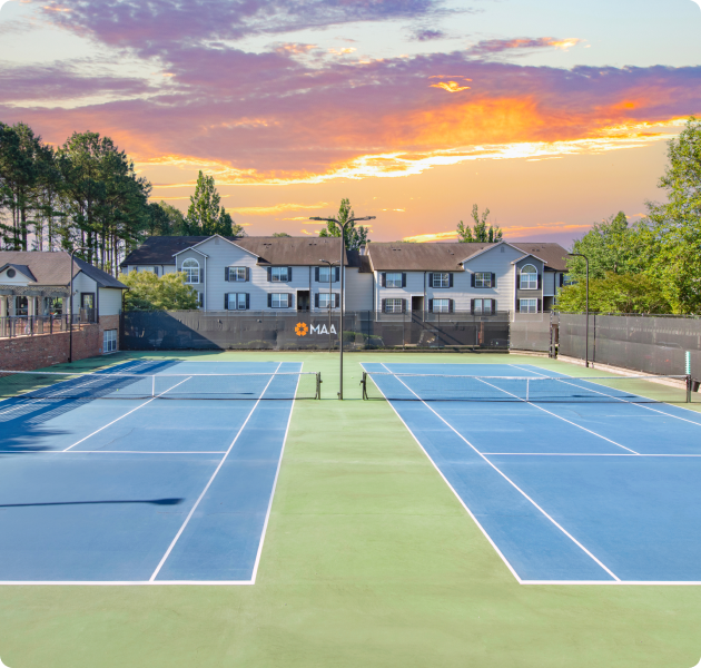 Community tennis courts surrounded by trees at sunset at MAA Oglethorpe luxury apartments in Atlanta, GA